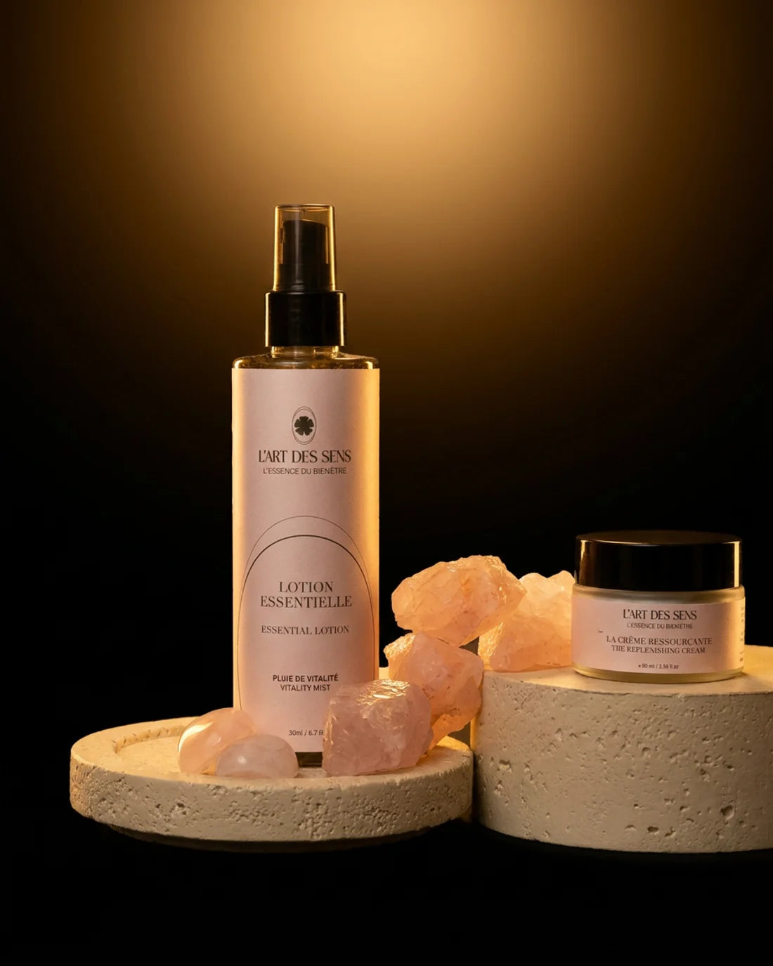 La gamme Ressource des Sens : la Lotion Essentielle et la Crème Ressourçante, entourées de quartz rose