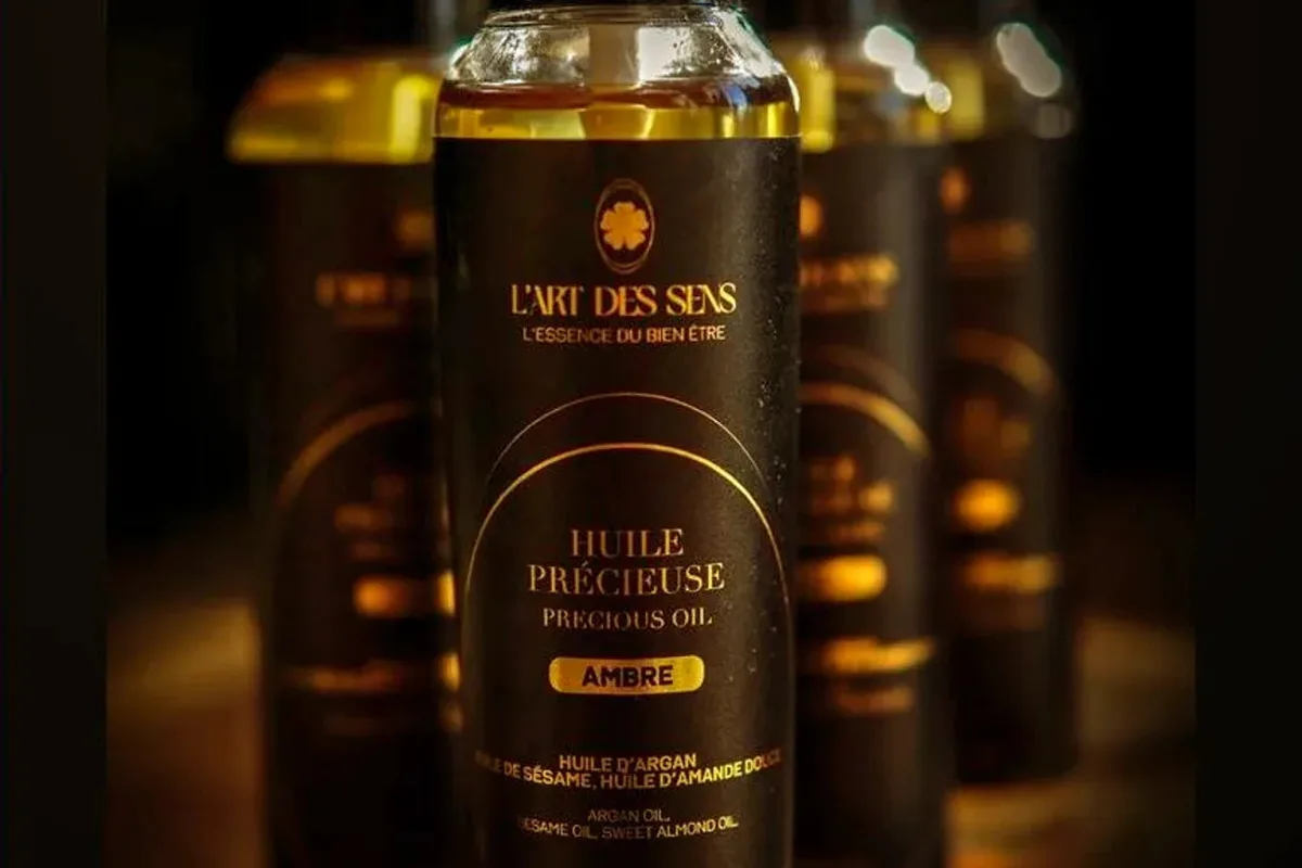 Flacons d’huiles précieuses à l’argan de L’Art des Sens, alignés sur fond sombre